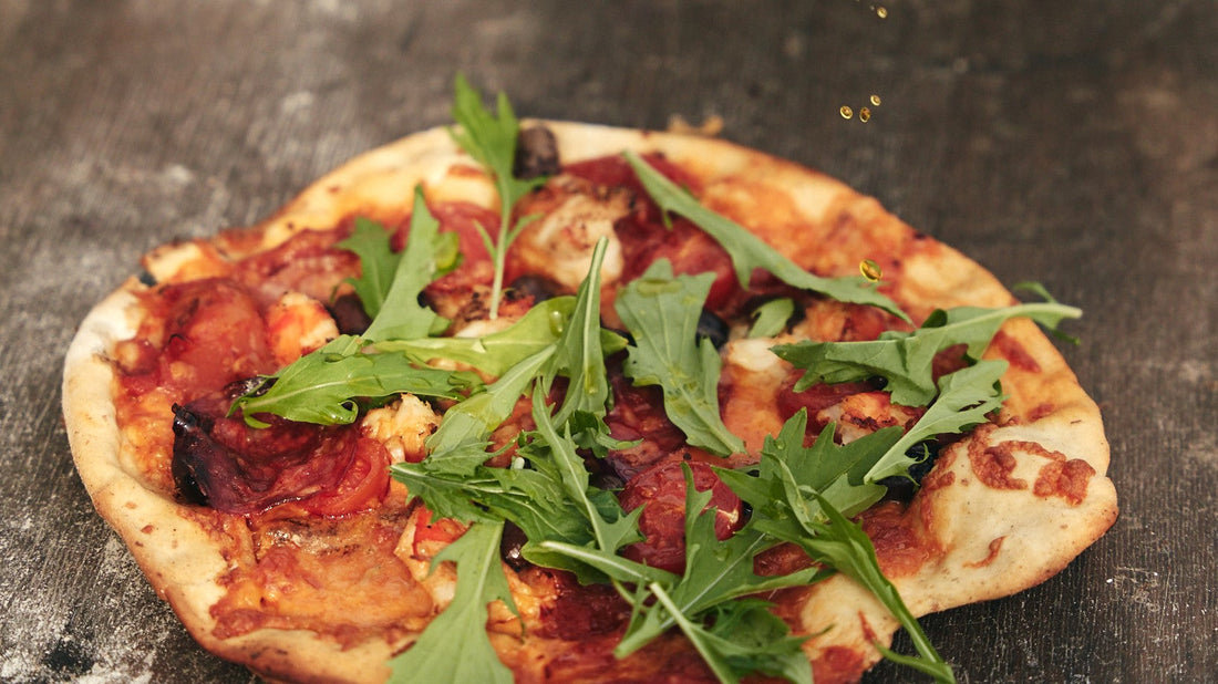 Pizza with leopard-spotted crust baking on a pizza stone inside a Bastard kamado